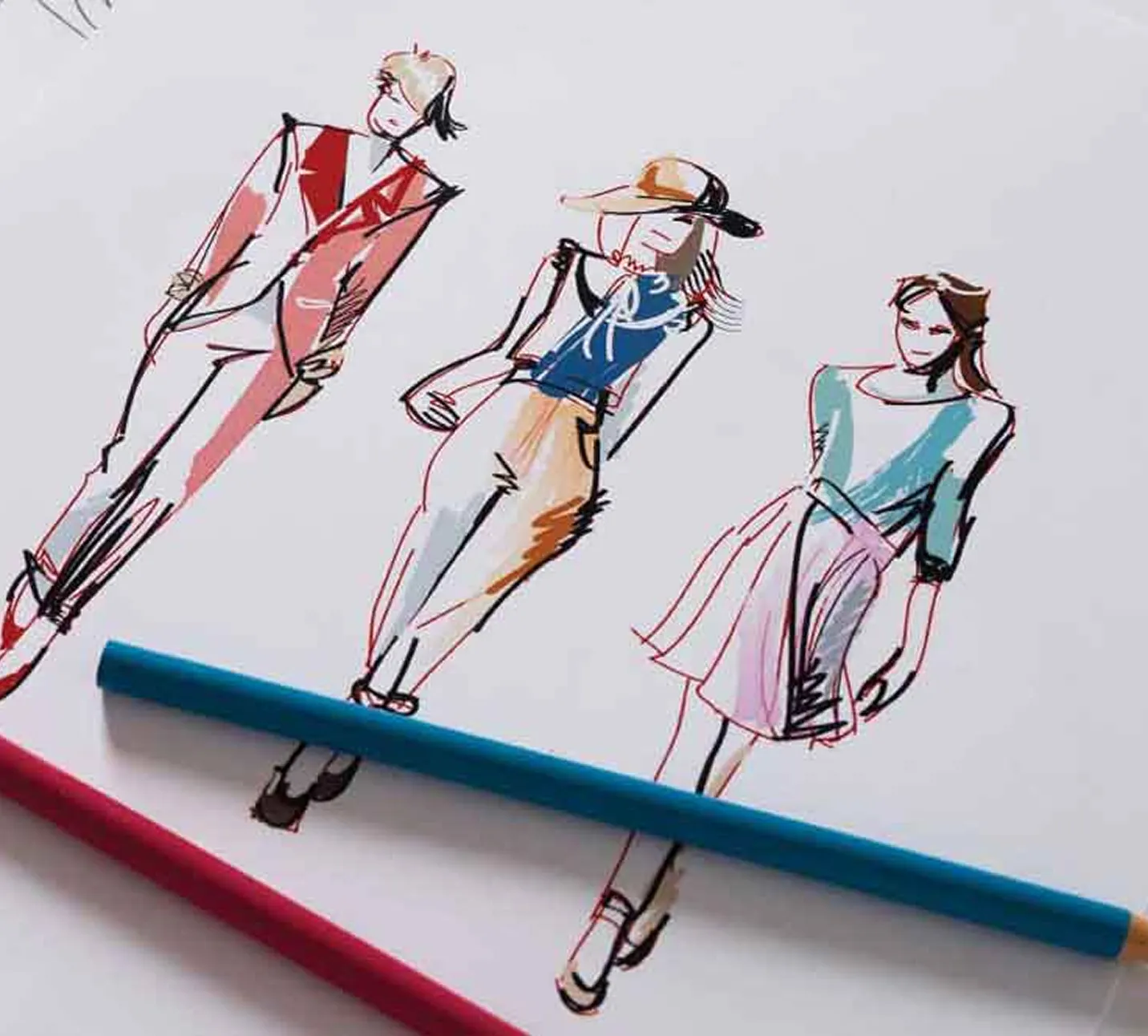 Fashion sketches of three models wearing different outfits, with two colored pencils lying below the drawings.